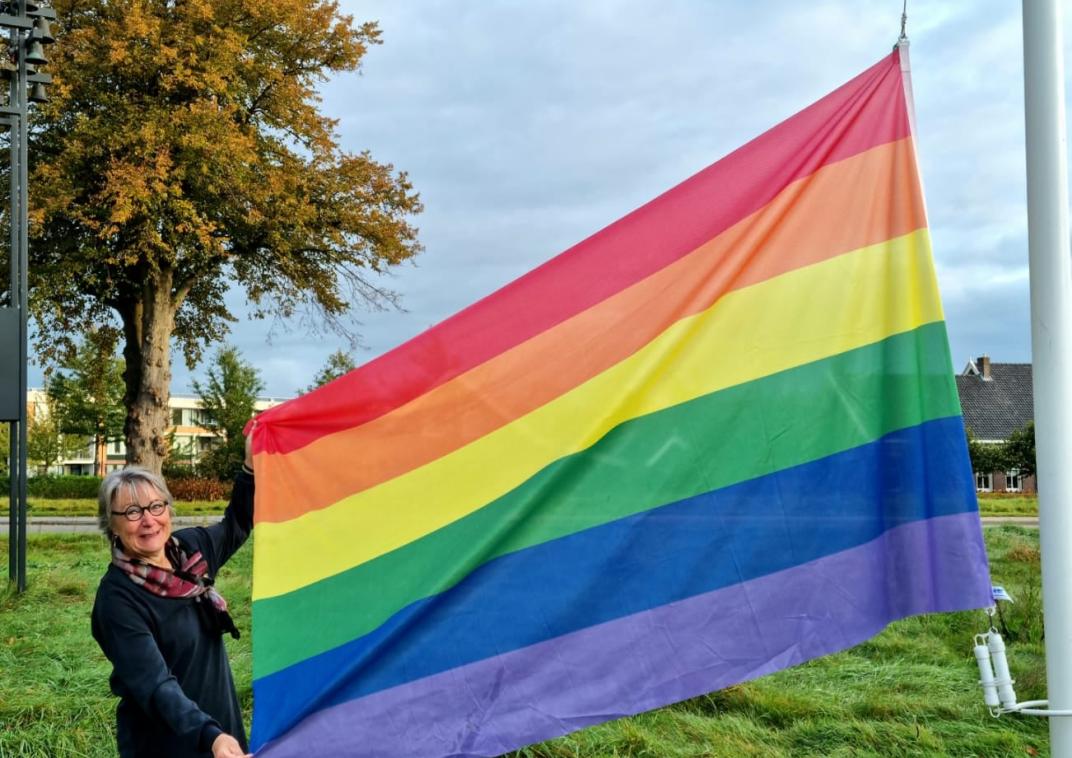Op de foto is te zien dat Marga de regenboogvlag hijst bij het gemeentehuis