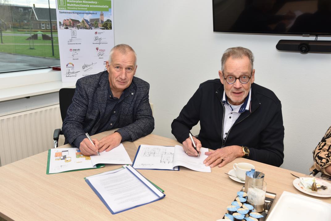 twee mensen aan een tafel ondertekenen contract
