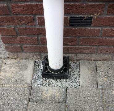 Foto van een ontlastputje onderaan een regenpijp.