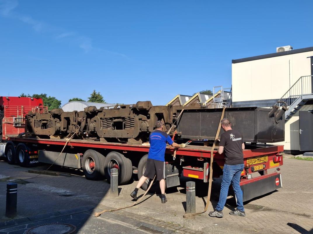 Laadwagen achter vrachtauto met twee werkmensen